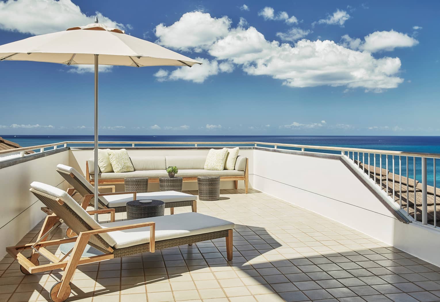 White cushioned wicker patio furniture, umbrella on rooftop balcony