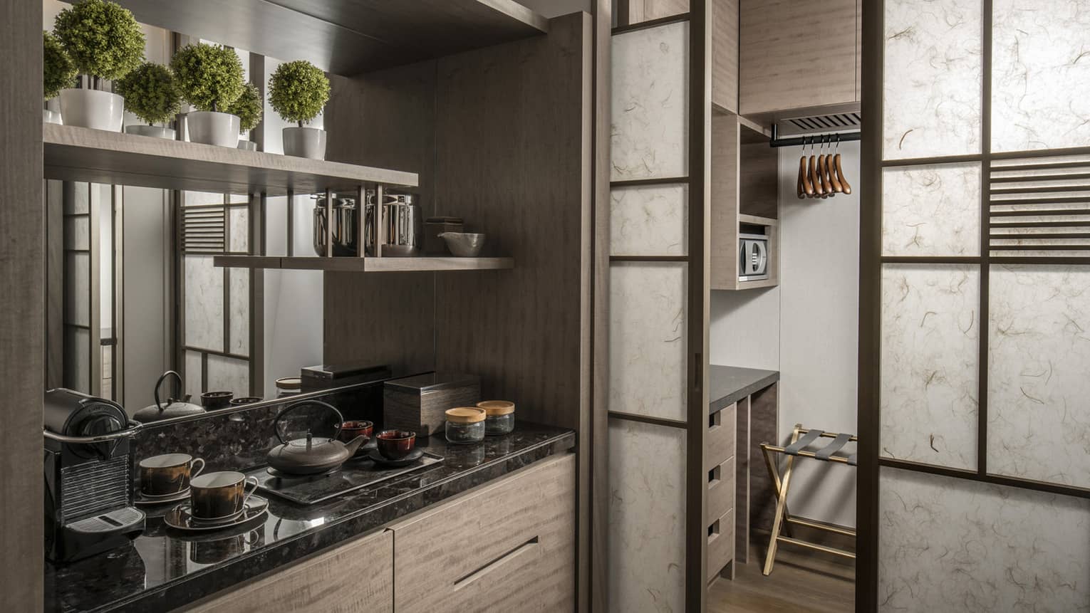 Compact kitchenette with a black granite countertop, open shelving and a pantry area with storage space and a small microwave