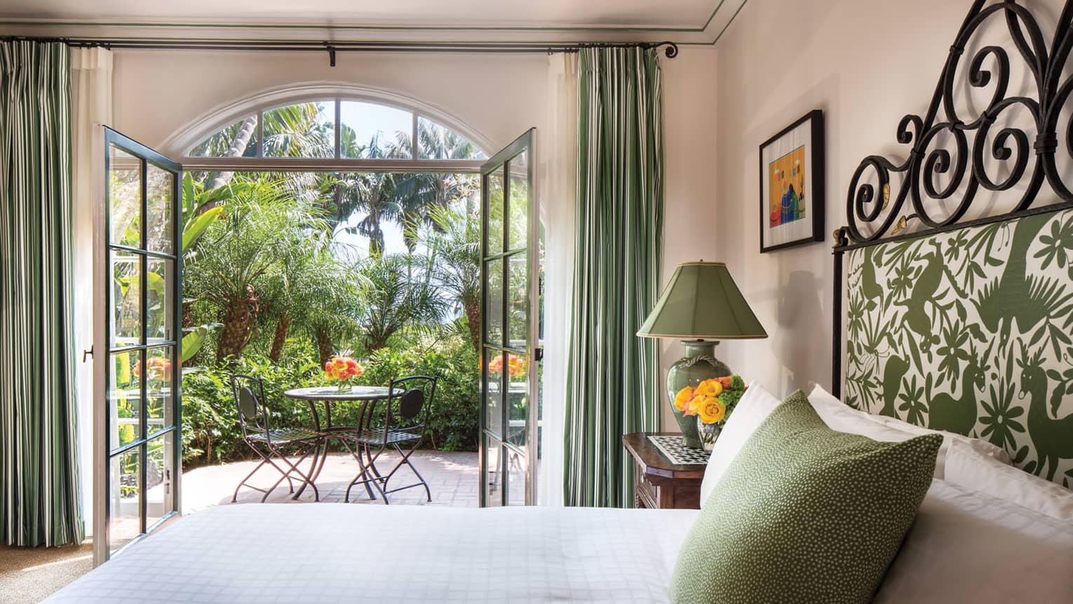 Garden Room open glass doors to sunny balcony, green lamp, pillow, headboard over bed