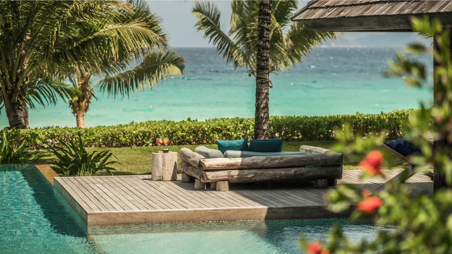 Kannel Bar swimming pool, wood deck, log loveseat looking out at palm trees, ocean