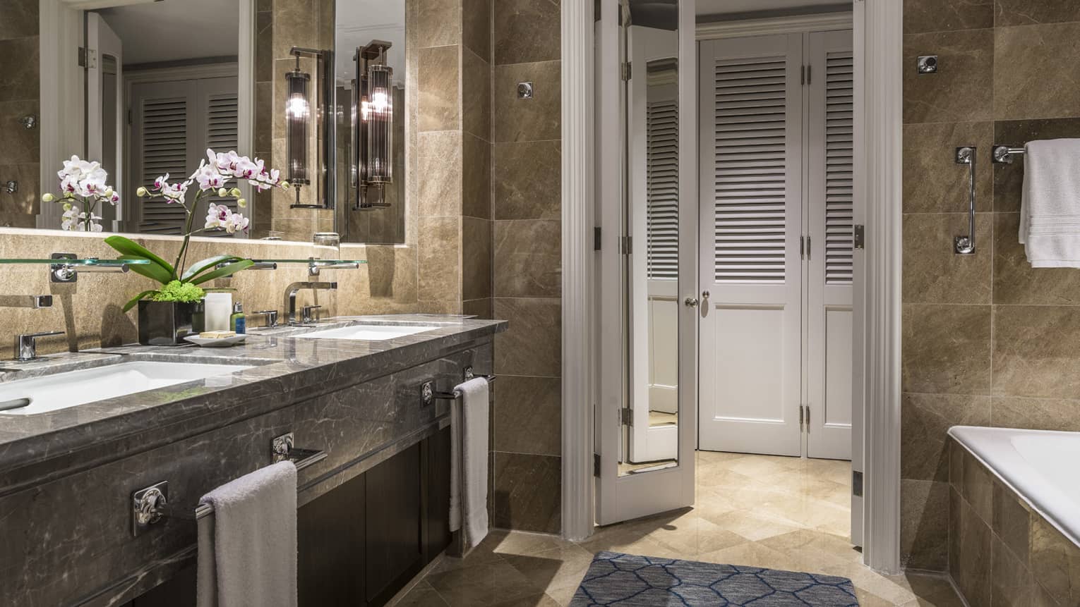 Luxurious bathroom featuring marble countertops, double sinks and elegant lighting.