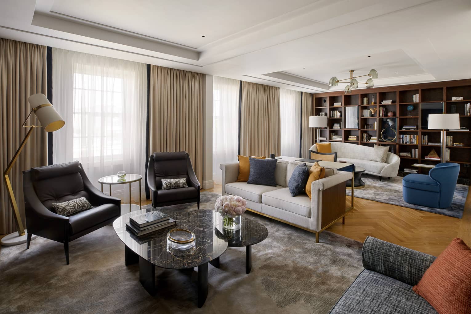 Living area with two black chairs and coffee table, grey loveseat in front of living area with white sofa, blue chair