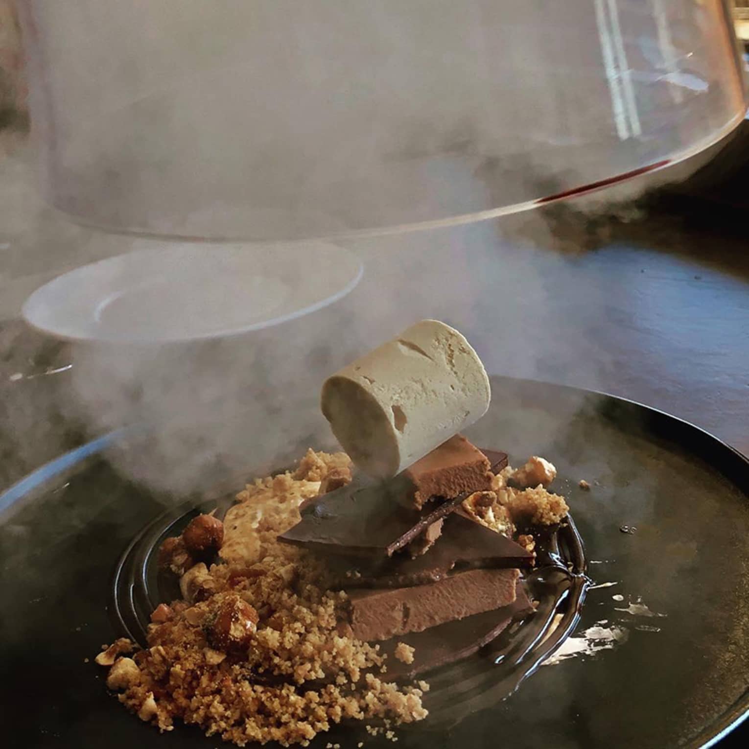 Glass lid revealing gourmet frozen dessert, steam