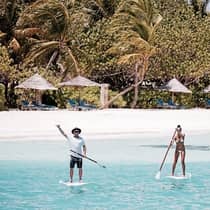 Man and woman hold paddles on stand up paddleboard in lagoon