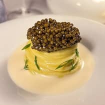 Spaghetti topped with a large portion of caviar, served in a cream coloured clam and almond sauce, garnished with fresh herbs