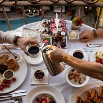 People eating an assortment of breakfast food and drinks, including coffee, fruit and waffles.