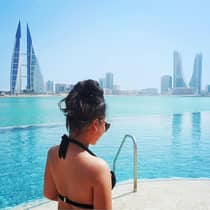 Woman in pool with Bahrain city view