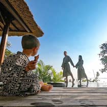Family wearing robes, young child sits cross legged on patio as parents hold hands in background