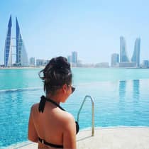Woman in pool with Bahrain city view