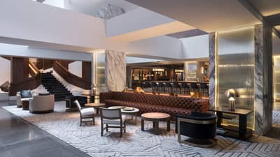 A lounge area with a bar, chairs and small tables.