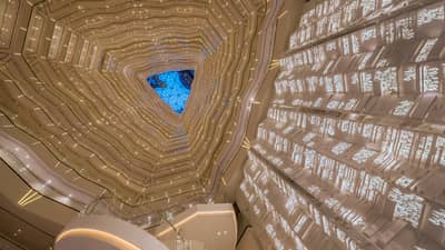 Triangular skylight seen past many floors of curved white balconies inside Four Seasons Hotel Guangzhou