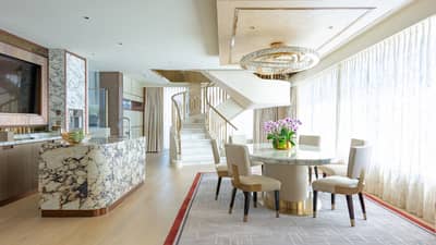 Dining area with round table and four chairs, chandelier, marble counter, spiral staircase in background