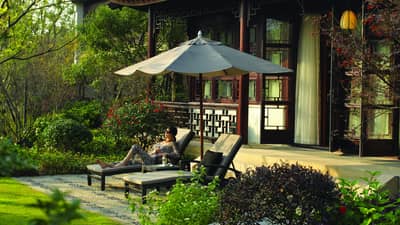 Royal West Lake Suite woman in zebra-striped outfit under umbrella on patio lounge chair