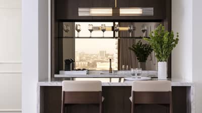 A kitchen with wine glasses on a shelf, herbs, two bar stools, an island and sink.