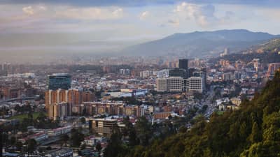 Aerial view of Bogota city, buildings and houses below misty mountains