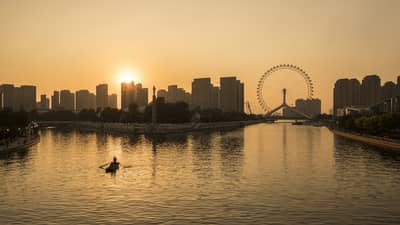 Silhouette of people in rowboat under Tianjin skyline, Eye ferris wheel at sunset