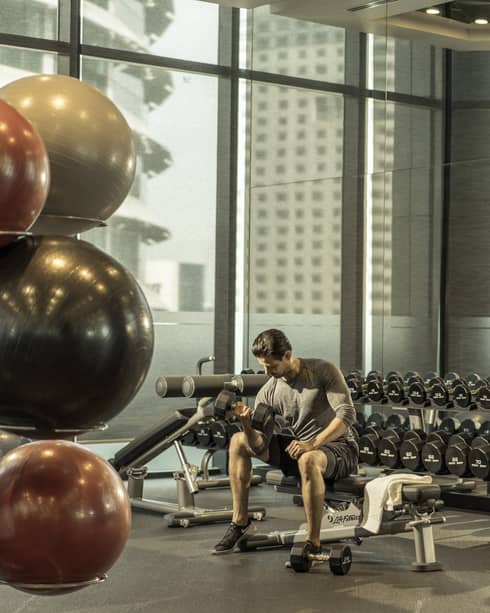 A man lifts weights in the gym at Four Seasons Hotel Kuala Lumpur