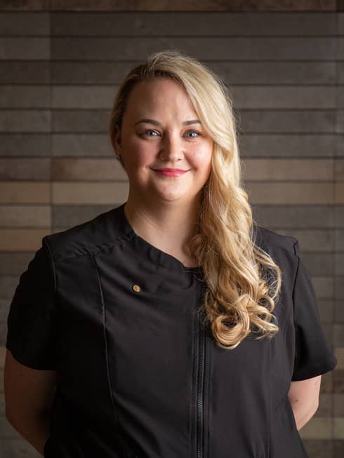Nicole Smiley standing with arms behind their back and smiling.