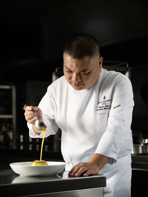 A chef working in the kitchen wears a white chefs coat with Four Seasons logo on it