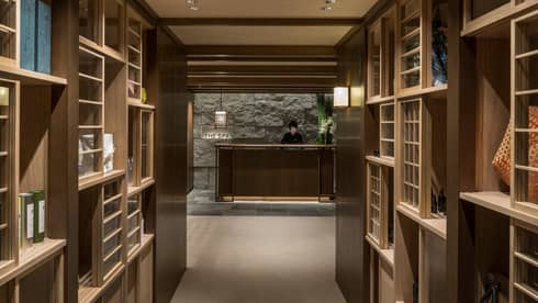 Wood shelves along hallway leading to dimly-lit The Spa reception desk, granite wall