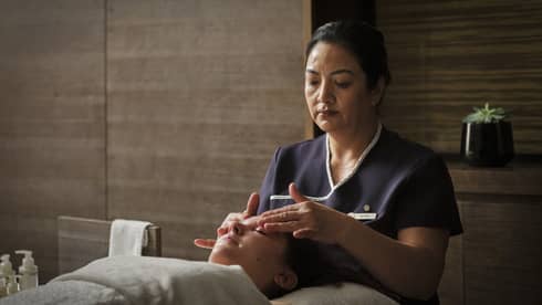 A spa team member giving a facial massage to a guest.