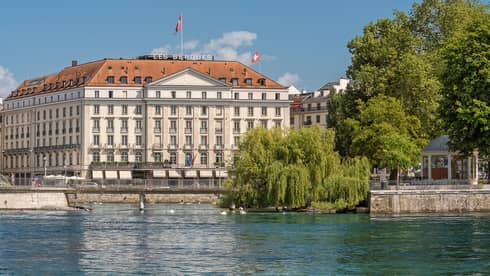 Exterior view of Four Seasons Hotel des Bergues historic building on sunny day by lake