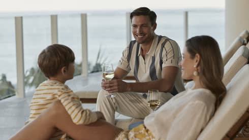Family lounging in outdoor chairs with glasses of wine.