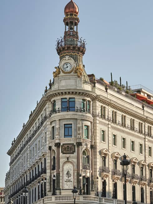 Historic ornate building with a clock tower, decorative ironwork and rooftop garden, featuring detailed stonework and balconies
