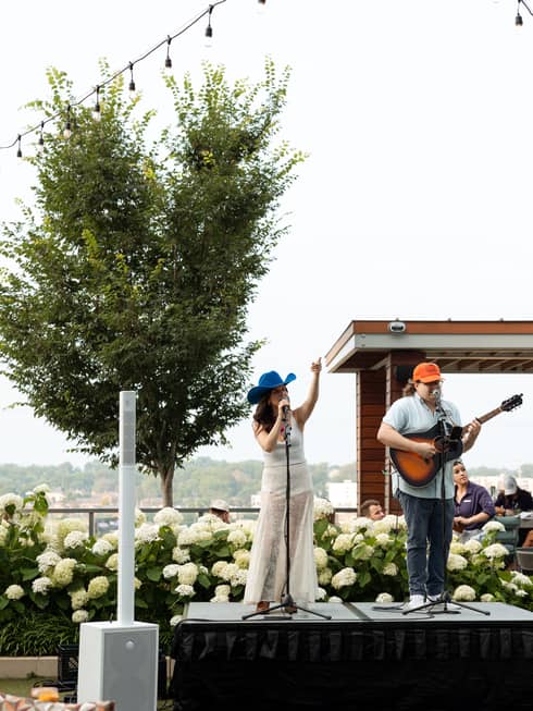 Two people on a stage singing and playing the guitar