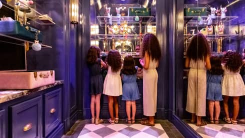 A mother and three young daughters looking at shelves in a closet.