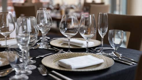 A dining table set with wine glasses, plates and napkins