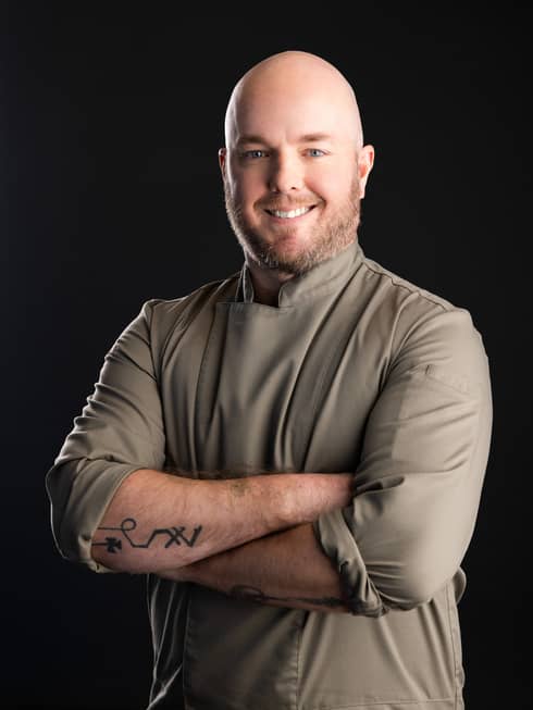 A chef in a light grey or beige chefs coat.