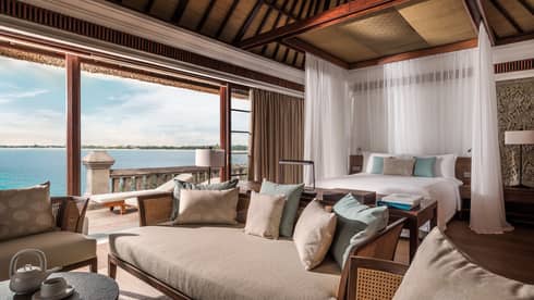 Family Premier Villa large bed with white drapes, sofa seating area, open wall to patio, ocean view