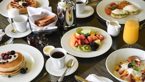 Breakfast feast with pancakes, fresh fruit, waffles, eggs Benedict, coffee and orange juice