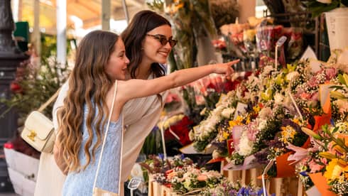 Two guests standing near a display of flowers at an outdoor shop