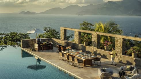 Aerial view of Four-Bedroom Residence Villa private deck with 8-person dining table beside pool, ocean view