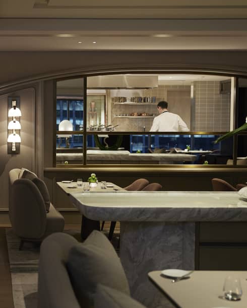 Dimly lit intimate dining area with lighted wall sconces, dark grey colour scheme