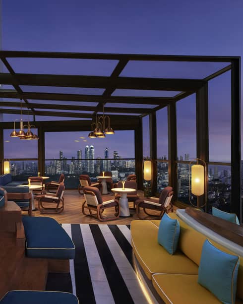 Four Season’s elegant rooftop bar, filled with comfortable seating and showing a stunning view of the city skyline at night.