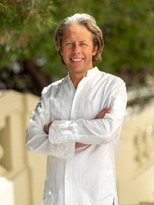 A chef in a white shirt standing in an outdoor setting