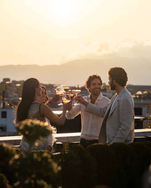 Four friends toasting on rooftop terrace at sunset