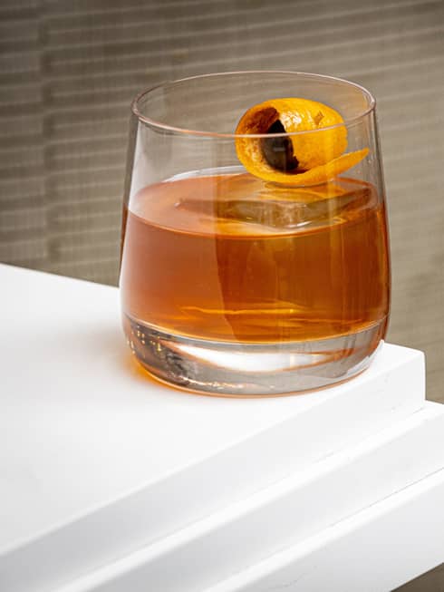 An amber coloured cocktail on a white counter.
