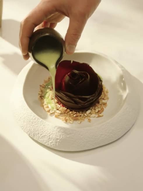 Pouring dressing over food with a flower in the middle.