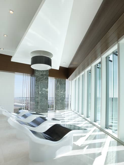 A row of four black-and-white loungers sit infront of a wall of windows in a hotel spa