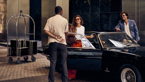 Man welcomes woman getting out of convertible car