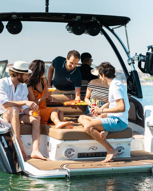 Four friends being served aperitivo on the back of a speedboat on Lake Geneva
