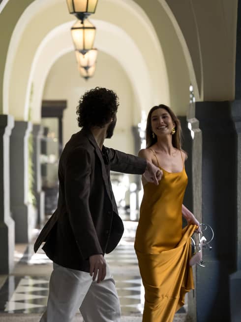 Two guests in a long arched hallway with a black and white tiled floor
