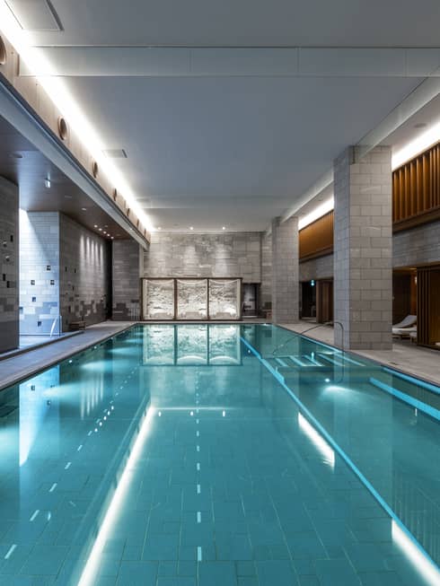 Indoor spa pool flanked by chaise longues and grey brick columns