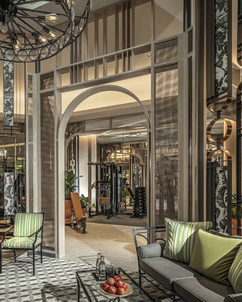 Fitness Centre lobby with high ceilings, round wrought-iron chandelier, sofa with green accent pillows