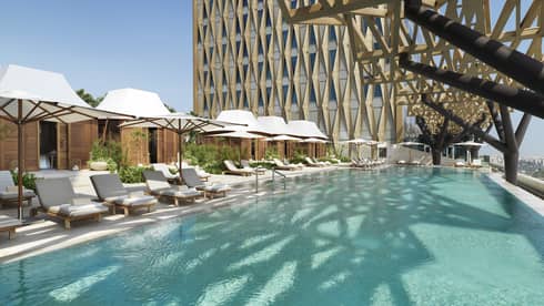 An olympic size pool surrounded by lounge chairs shaded by large white umbrellas