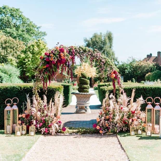 Wedding floral arch surrounded by candles and smaller floral arrangements